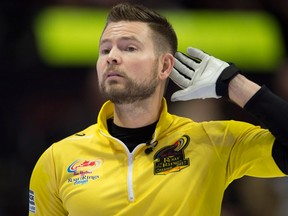 Skip Mike McEwen, from Winnipeg, gestures to teammates that he can't hear them as they debate a shot from opposite ends of the ice during the Olympic curling trials, on Dec. 4, 2017