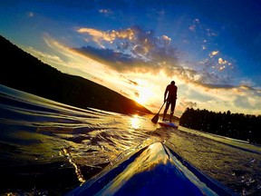Stand up paddle boarders make their way towards the setting sun at Meech Lake.