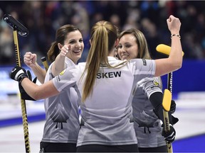 Emma Miskew pumps her fist as she celebrates with Rachel Homan, right, and Lisa Weagle after defeating Jennifer Jones in the women's semifinal on Saturday at Canadian Tire Centre.