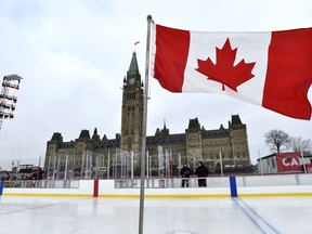 A Canadian flag standing on the ice flies in front of Centre Block before the official inauguration of the Canada 150 Rink on Parliament Hill in Ottawa on Thursday, Dec. 7, 2017.