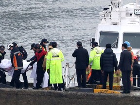 South Korean police officers and rescue workers carry a victim of a boat capsizing at a port in Incheon, South Korea, Sunday, Dec. 3, 2017. A fishing boat collided with a refueling vessel and capsized, the country's coast guard said.