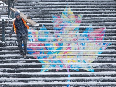 A construction worker carries a board down the York Street Steps as the region begins to deal with the first major snowfall of the winter.