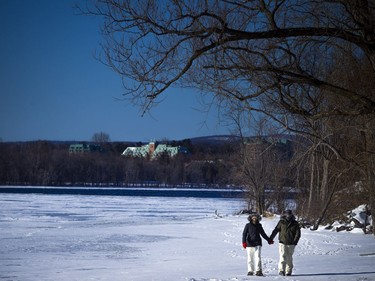 A couple walks along the edge of the Ottawa River by Westboro Beach.