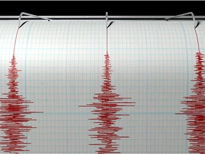 A closeup of a seismograph machine needle drawing a red line on graph paper depicting seismic and earthquake activity on an isolated white background.