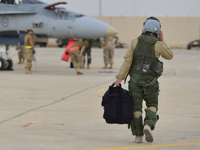 A Royal Canadian Air Force CF-18 Hornet fighter jet pilot from 4 Wing Cold Lake, Alberta walks down the flight line in Kuwait after his first combat mission over Iraq in support of Operation IMPACT on October 30, 2014.