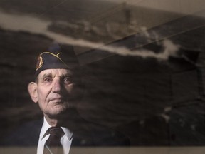 Ret. Merchant Navy Captain Paul Bender, 90, is reflected in a picture of the war ship he worked on while in his Ottawa home Tuesday, December 19, 2017. Bender is campaigning to designate wartime shipwrecks as ocean war graves, a special heritage designation