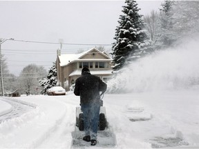 A man with a snowblower creates a path for a vehicle stuck in the snow.