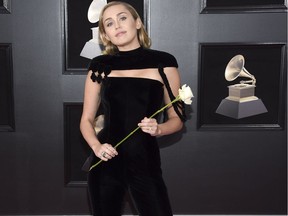 Miley Cyrus holds a white rose as she arrives at the 60th annual Grammy Awards at Madison Square Garden on Sunday, Jan. 28, 2018, in New York.