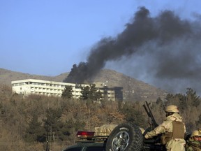 In this Jan. 21 photo, Afghan security personnel stand guard as black smoke rises from the Intercontinental Hotel after an attack in Kabul. U.S. policy there remains contradictory.