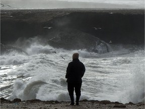 A man walks along the coast during a storm.