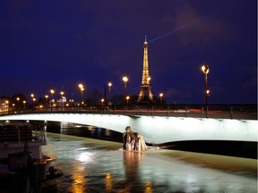 This photo taken on January 25, 2018 in Paris shows an illuminated Eiffel Tower, next to the Seine River, with water levels raised to the height of the Zouave statue of the Pont d'Alma bridge.  The Seine continued to rise on January 25, 2018, flooding streets and putting museums on an emergency footing as record rainfall pushed rivers over their banks across northeastern France.