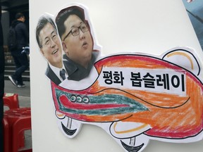 In this Tuesday, Jan. 16, 2018, photo, pictures of South Korean President Moon Jae-in, left, and North Korean leader Kim Jong Un are seen on a sign during a rally for a peaceful Winter Olympics in Seoul, South Korea. North Korea plans to send a spotlight-stealing delegation to next month's Winter Olympics in the South Korean county of Pyeongchang. The letters read "Peace bobsleigh."
