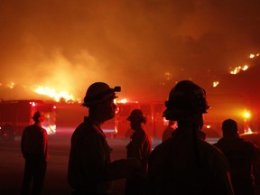 Firefighters gather in front of a residential area as a wildfire burns along the 101 Freeway in Ventura, Calif.