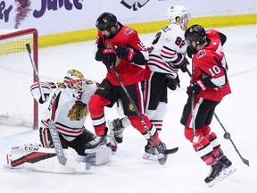 Chicago Blackhawks goalie Anton Forsberg braces for a shot with teammate Jordan Oesterle (82) against Ottawa Senators' Zack Smith (15) and Tom Pyatt (10) during the first period of NHL hockey action in Ottawa on Tuesday, Jan. 9, 2018.