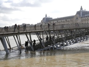 People watch the Seine river from the Leopold-Sedar-Senghor bridge in Paris, France, Friday, Jan. 26, 2018 The Paris region has been deeply affected by the floods that hit the country over the past week, but in Paris, it was business as usual.