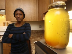Lucien Malolo stands near a jar of sewage that ran through her cabinets in her kitchen in her Ottawa home.