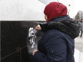 Members of the Jami Omar Mosque remove hate posters in Ottawa on Tuesday, Jan. 30, 2018.