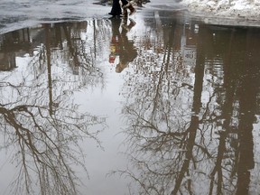 Kids walk near a giant puddle.