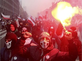 File photo, far-right nationalists burn flares as they march in large numbers through the streets of Warsaw to mark Poland's Independence Day in Warsaw, Poland. Poland's government is facing pressure to deal with the phenomenon of a rising far-right following the weekend broadcast of an explosive report about Polish neo-Nazis.