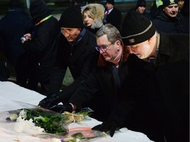 Prime Minister Justin Trudeau, left to right, Quebec City mayor Regis Labeaume and Quebec Premier Philippe Couillard place flowers in front of a mosque during a vigil to commemorate the one-year anniversary of the Quebec City mosque shooting in Quebec City, Monday, Jan. 29, 2018.