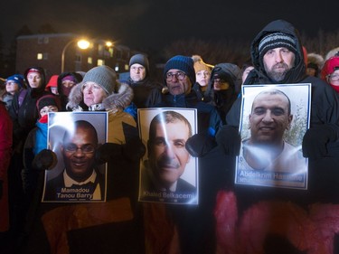 People hold pictures of the victims at a vigil to commemorate the one-year anniversary of the Quebec City mosque shooting, in Quebec City, Monday, Jan. 29, 2018.