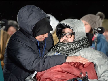 Aymen Derbali, a victim who was shot seven times, is comforted during a vigil to commemorate the one-year anniversary of the Quebec City mosque shooting in Quebec City, Monday, Jan. 29, 2018.