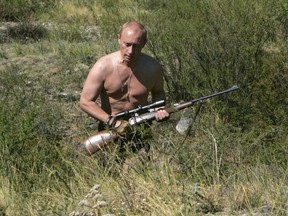 In this Sept. 2010 photo released on Saturday, Oct. 30, 2010, then-Russian Prime Minister Vladimir Putin carries a hunting rifle during his trip in Ubsunur Hollow in the Siberian Tyva region on the border with Mongolia, Russia.