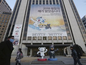 People pass a banner promoting the upcoming 2018 Pyeongchang Winter Olympics.