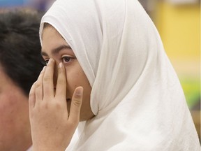 The 11-year-old child who alleged that a man had tried to cut her hijab with a pair of scissors wipes a tear from her eye during a news conference on Friday, Jan. 12 in Toronto.