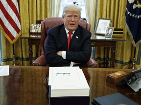 U.S. President Donald Trump speaks with reporters after signing the tax bill and continuing resolution to fund the government, in the Oval Office of the White House in Washington.