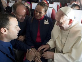 Pope Francis marries flight attendants Carlos Ciuffardi, left, and Paola Podest, center, during a flight from Santiago, Chile, to Iquique, Chile, Thursday, Jan. 18, 2018. Pope Francis celebrated the first-ever airborne papal wedding, marrying these two flight attendants from Chile's flagship airline during the flight. The couple had been married civilly in 2010, however, they said they couldn't follow-up with a church ceremony because of the 2010 earthquake that hit Chile. (L'Osservatore Romano Vatican Media/Pool Photo via AP)