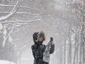 A woman takes pictures as snow falls around her.