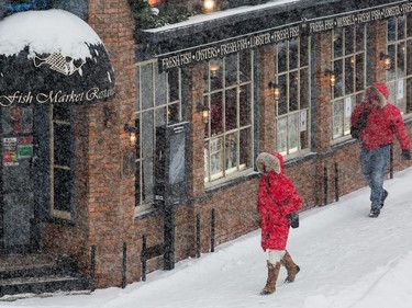 Pedestrians in the Byward Market as the region experiences continuing snowfall on Monday.