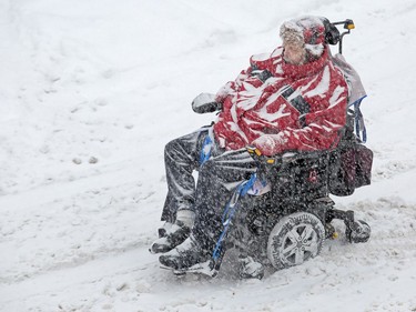 Glen Forrester navigates the sloppy streets in his wheelchair in the Byward Market as the region experiences continuing snowfall on Monday.