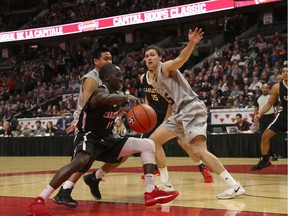 Carleton's Munis Tutu dribbles the ball into the heart of the Ottawa defence, including Brody Maracle, right, during the men's Capital Hoops Classic basketball game at Canadian Tire Centre on Friday night. Munis finished the contest with eight points. Jana Chytilova/Postmedia