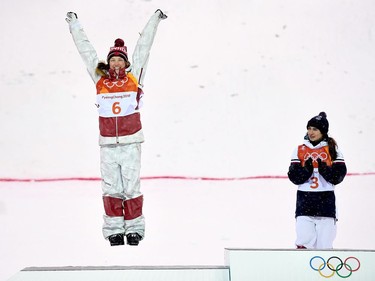 Gold medal winner, France's Perrine Laffont, right, looks on as Canada's Justine Dufour-Lapointe, of Montreal, celebrates with a jump on the podium after competing to her silver medal finish in the freestyle skiing event at the 2018 Winter Olympic Games, in Pyeongchang, South Korea, on Sunday, February 11, 2018.