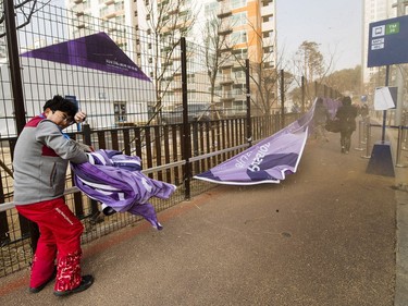 An Olympic worker takes cover from extreme wind gusts at the media village at the 2018 Olympic Winter Games in Gangneung, South Korea on Wednesday, February 14, 2018.