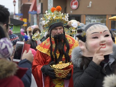 Richard Martin, volunteer for Chinese New Year celebration dressed as king of fortune gives out red envelopes for money and good fortune on Saturday, Feb. 17, 2018.