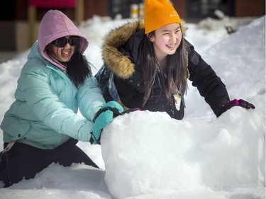 14-year-old Cynthia Lem put her muscles behind moving a big chunk of ice and snow with the help of (left) 12-year-old Alicia Wang. The Crackup Snowmania Challenge took place Saturday Feb 17, 2018 at Lansdowne Park.