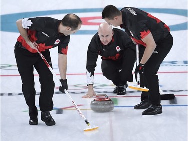 Canada skip Kevin Koe plays a stone as second Brent Laing, left, and lead Ben Hebert get ready to sweep during men's semifinal curling action against the USA at the 2018 Winter Olympics in Gangneung, South Korea, Thursday, Feb. 22, 2018