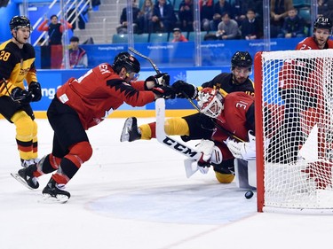 Germany's Yasin Ehliz (C) and Canada's Kevin Poulin (front R) look at the puck in the men's semi-final ice hockey match between Canada and Germany during the Pyeongchang 2018 Winter Olympic Games at the Gangneung Hockey Centre in Gangneung on February 23, 2018.