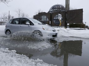 A car rolls through a large puddle.