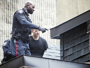 Ottawa police led a man to an ambulance in handcuffs after fire crews helped rescue him off of a roof at 341 Gloucester Street Sunday Feb. 25, 2018.   Ashley Fraser/Postmedia