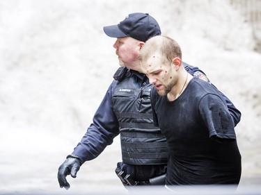 Ottawa police led a man to an ambulance in handcuffs after fire crews helped rescue him off of a roof at 341 Gloucester Street Sunday Feb. 25, 2018.   Ashley Fraser/Postmedia