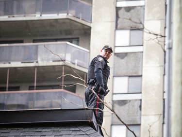 Ottawa police led a man to an ambulance in handcuffs after fire crews helped rescue him off of a roof at 341 Gloucester Street Sunday Feb. 25, 2018.   Ashley Fraser/Postmedia