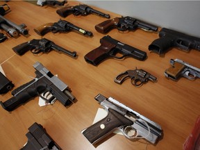 Seized guns, cash and evidence photographs of drugs on display at a news conference at the Ottawa police headquarters in December 2017.