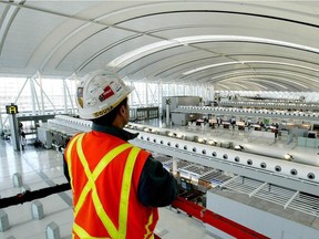 Aecon Construction scissor lift operator, Abel Sousa, looks at Toronto Pearson International Airport's new Terminal 1 check-in area from above the scissor lift on Tuesday Dec. 2, 2003.