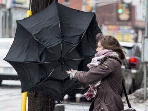 A woman struggles with her umbrella in the wind and rain in downtown Ottawa Tuesday morning.