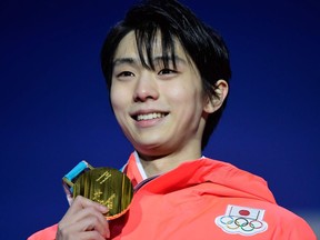 Yuzuru Hanyu poses on the podium after receiving the gold medal for men's singles figure skating on Saturday.