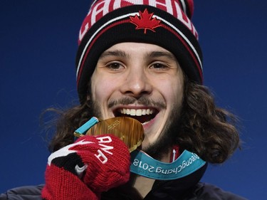 Canada's gold medallist Samuel Girard bites his medal on the podium during the medal ceremony for the short track men's 1000m at the Pyeongchang Medals Plaza during the Pyeongchang 2018 Winter Olympic Games in Pyeongchang on February 18, 2018.